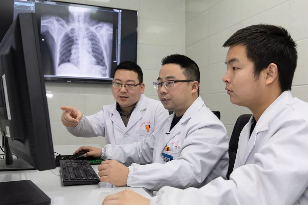 Three doctors are looking at the screen.
